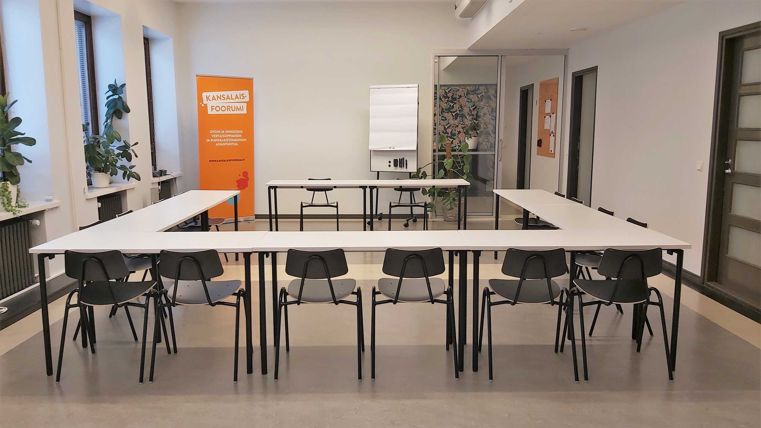 Meeting room furnished with chairs and tables, which are arranged in u-form.