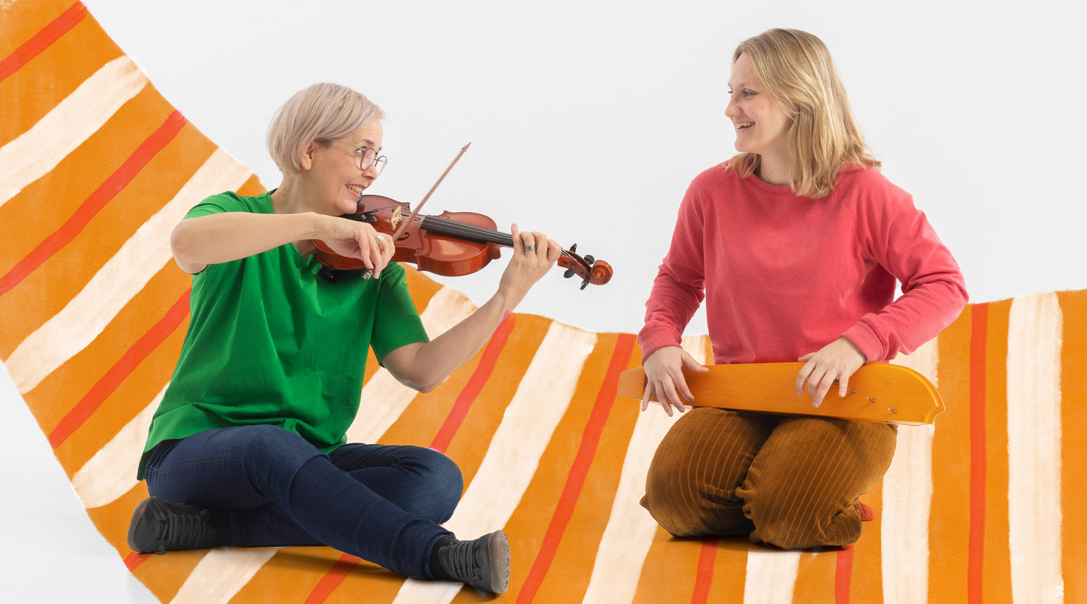 Kaksi naista istuu lattialla. Toinen naisista soittaa viulua, toinen kanteletta. Kuvaan on lisätty piirroskuvituksen muodossa raidallinen matto.